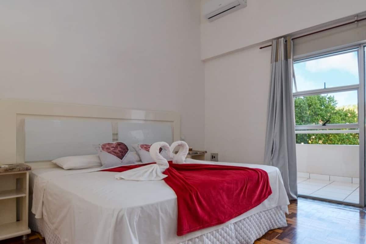 Ein Hotelzimmer mit einem großen Bett, einer roten Decke und zwei weißem Kissen in Form von Schwänen.