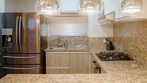 A modern kitchen with stainless steel appliances, granite countertops, and pendant lighting. - Hermosas piscinas, solo a 5 minutos del mar y salida directa a centro comercial. (Bello Horizonte, Santa Marta)