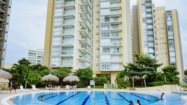 A swimming pool surrounded by high-rise residential buildings with balconies. - Hermosas piscinas, solo a 5 minutos del mar y salida directa a centro comercial. (Bello Horizonte, Santa Marta)