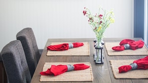A dining table set with red napkins and a vase of flowers. A vintage poster with cherries and the text "Seek Happiness" is on the wall. - Cozy Cottage perfect for a couple or small family (Durango)