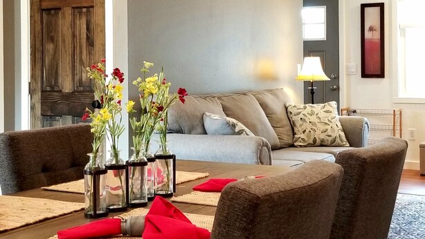 A dining area with a wooden table, chairs, and a vase with flowers. - Cozy Cottage perfect for a couple or small family (Durango)