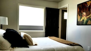 A bedroom with a bed, a window, a painting, and a door. - Cozy Cottage perfect for a couple or small family (Durango)