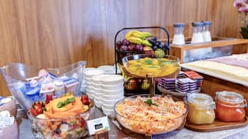 Buffet amb diferents plats, incloent fruita, amanides i salses.
