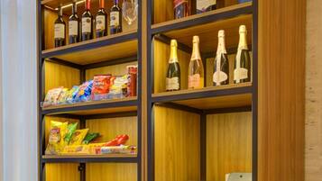 Un quiosco autoservicio con un terminal de pago, rodeado de estantes llenos de bocadillos y bebidas.