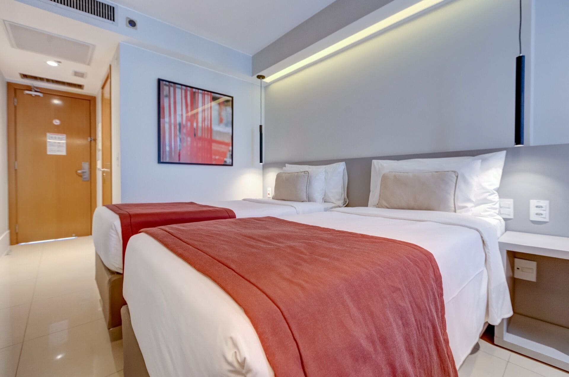 A hotel room with two beds, a large abstract painting, and a modern design.