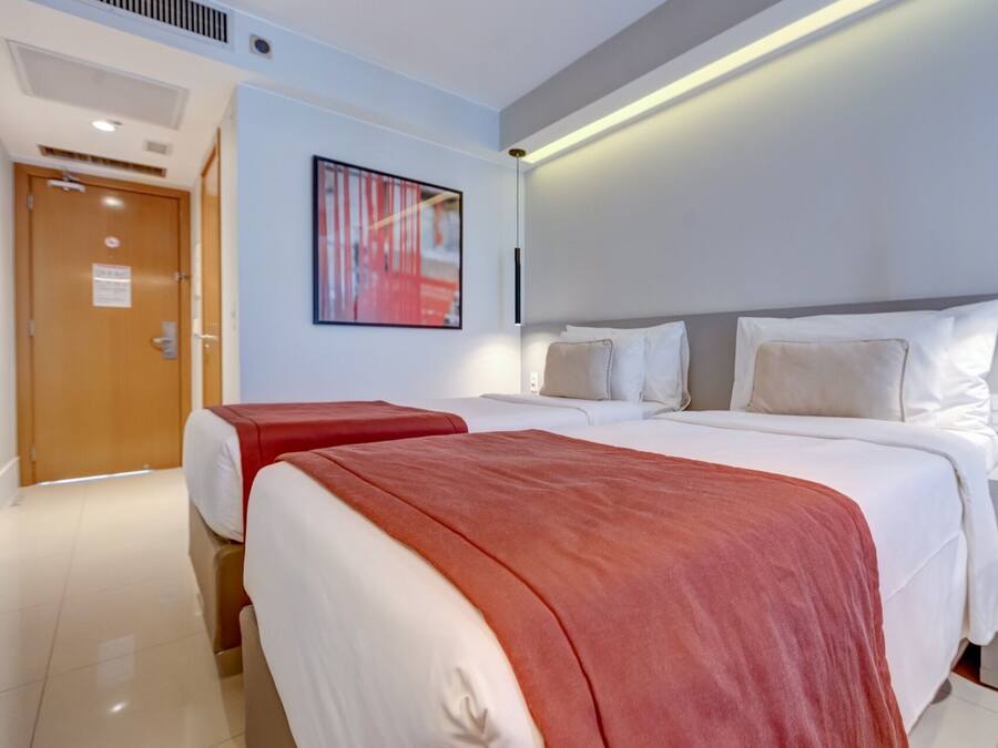A hotel room with two beds, a large abstract painting, and a modern design.