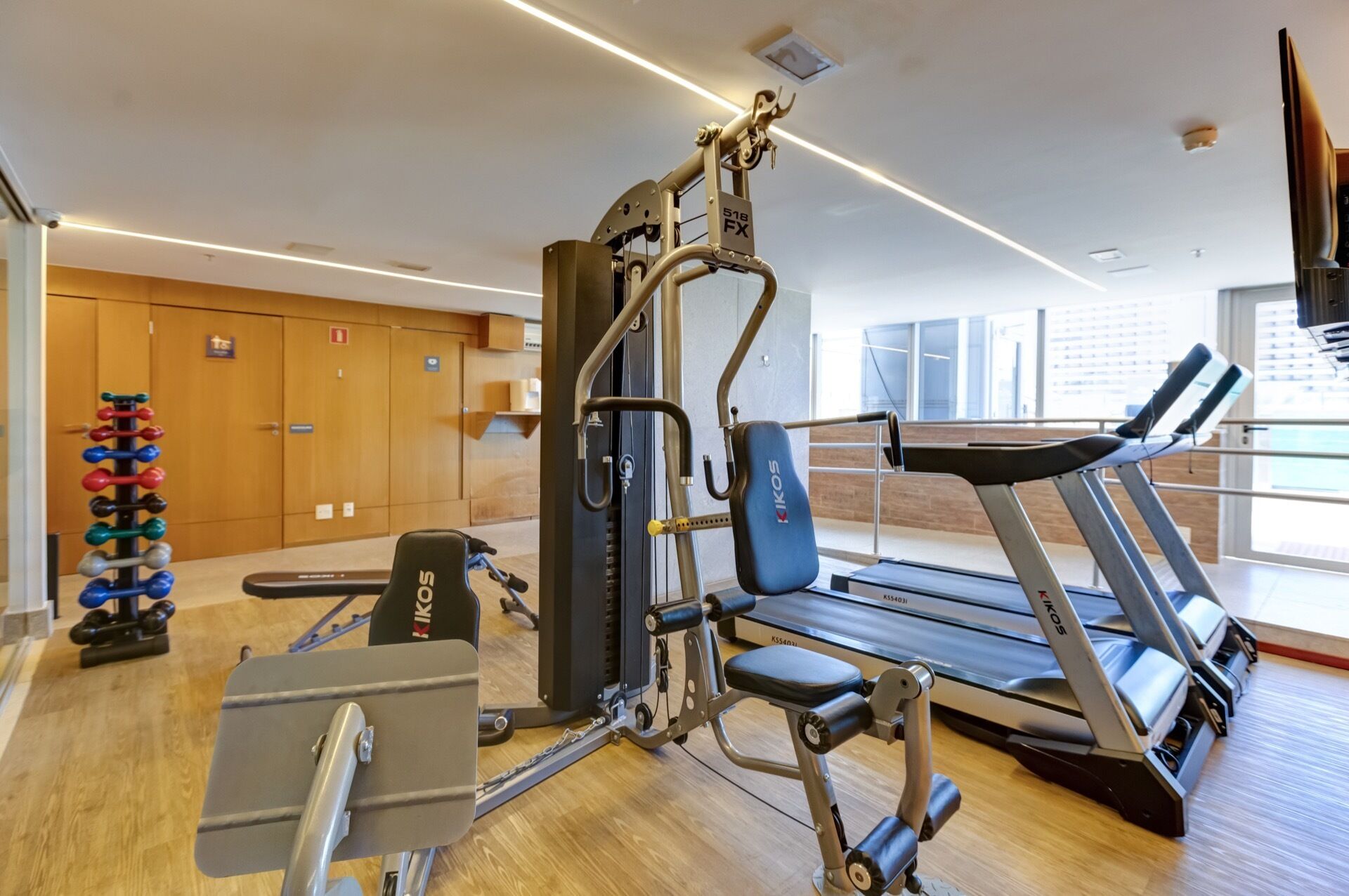 A gym with cardio equipment, weight machines, and dumbbells.