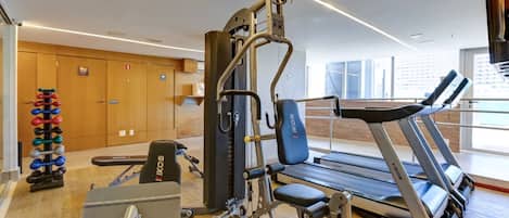 A gym with cardio equipment, weight machines, and dumbbells.