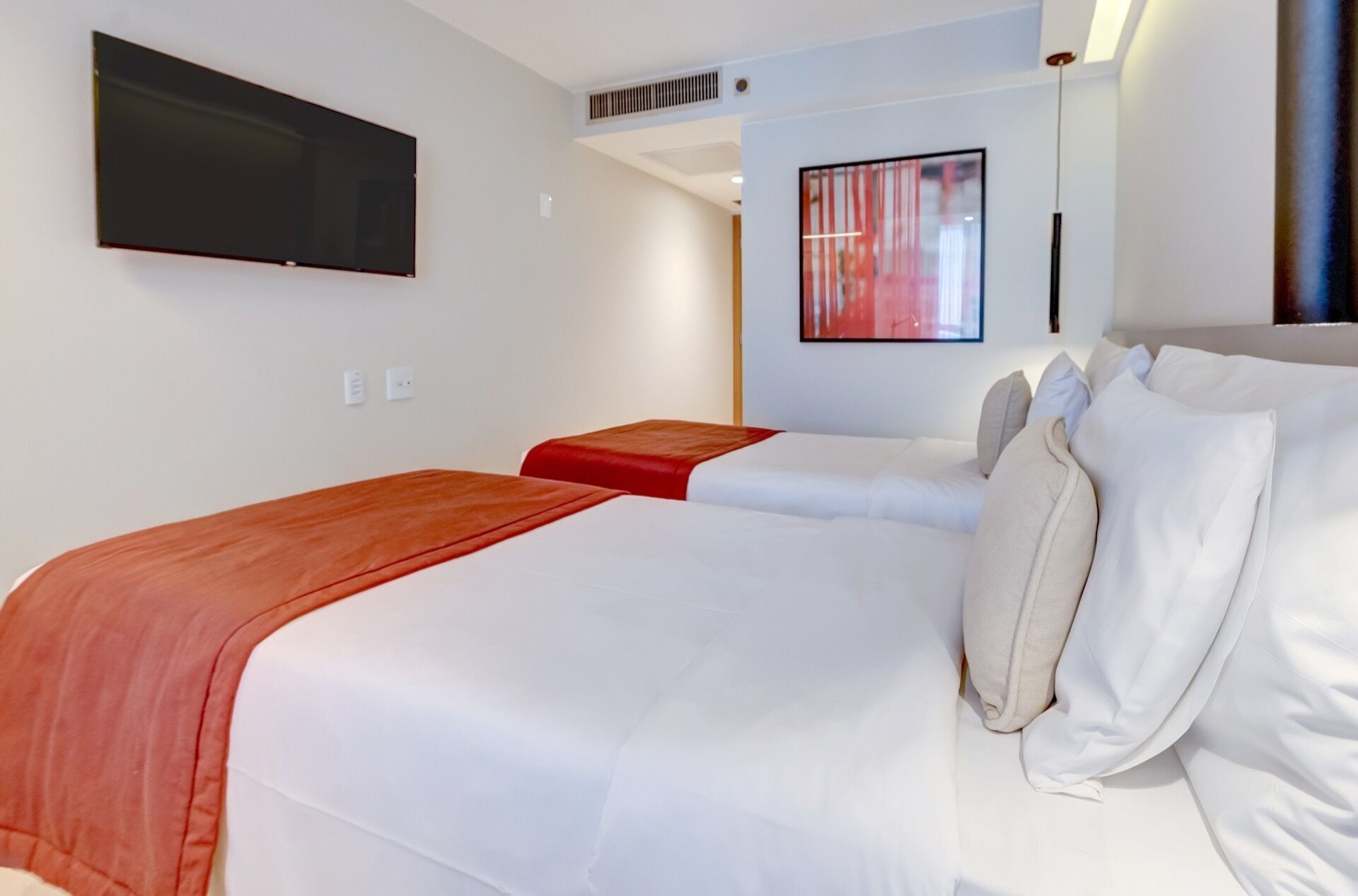 Habitación de hotel con dos camas, un televisor de pantalla plana, un cuadro y un diseño moderno.