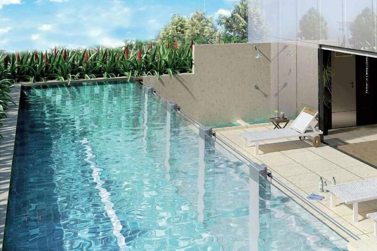 Una piscina rectangular con agua cristalina, rodeada por una solana con baldosas. Hay sillas de descanso y una pequeña mesa en la solana.