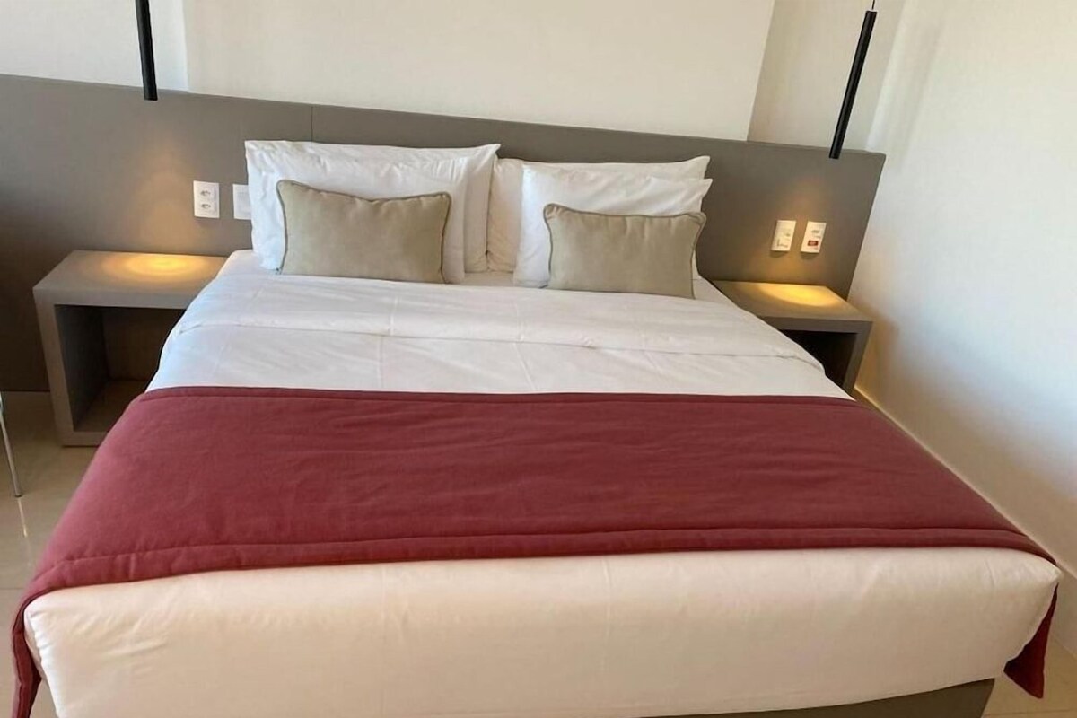 Een moderne hotelkamer met een groot bed, twee nachtkastjes en een neutraal kleurenschema.