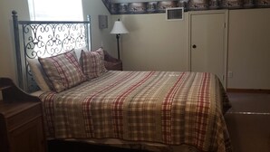 Un dormitorio con cama, mesita de noche, lámpara y armario.