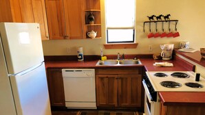 Una cocina compacta con armarios de madera, lavavajillas, estufa y ventana con vistas.