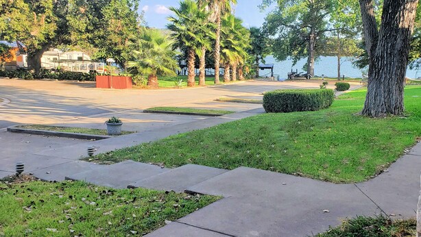 Un parque con un camino pavimentado, césped y árboles.