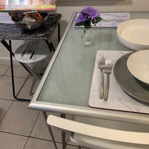 Enjoy meals in this cozy dining area with a glass table, comfortable chair, and stool.