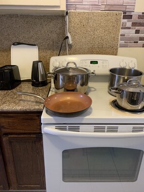 Kitchen equipped with a stove, pots, and a frying pan, along with a toaster and coffee maker.