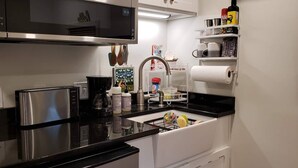 Eine kleine Küche mit Mikrowelle, Toaster, Spüle und verschiedenen Küchengeräten.