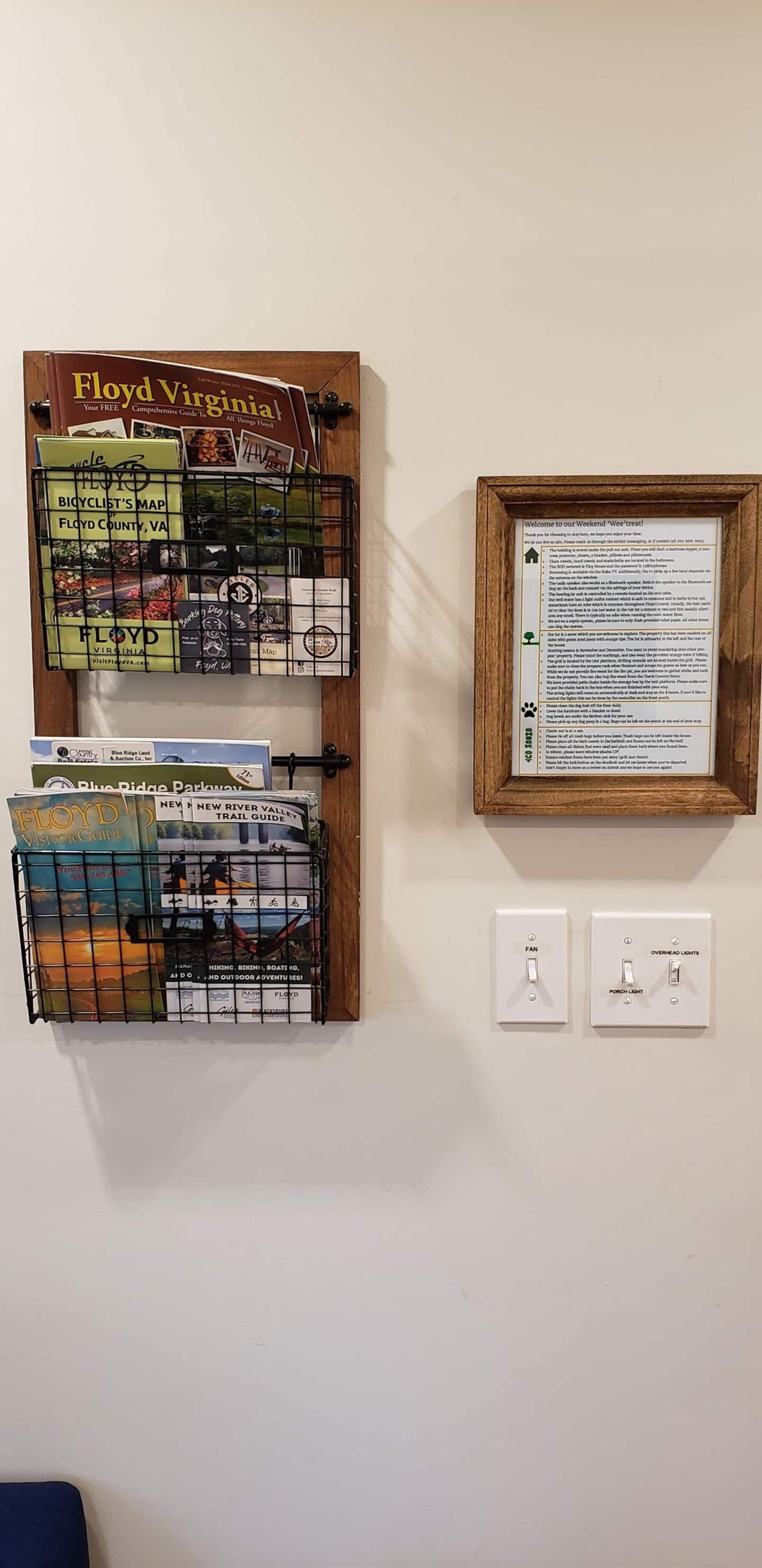 A wall-mounted display with various travel guides and maps, including a 'Floyd Virginia' guide and a 'New River Valley Trail Guide'.