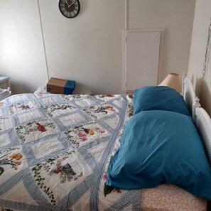 A bedroom with a bed, a clock on the wall, and a box on the floor.