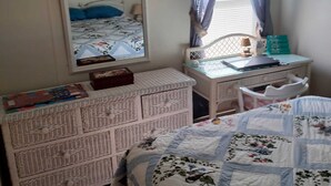 Un dormitorio con cama, cómoda, escritorio y espejo.