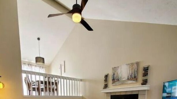 A living room with a fireplace, a ceiling fan, a sofa, and a coffee table. - West Omaha Gem • Near Trails, Parks & Dining ❤ (Omaha)