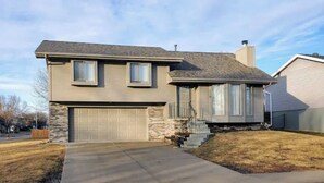 A two-story house with a garage, a stone facade, and a front yard. - West Omaha Gem • Near Trails, Parks & Dining ❤ (Omaha)
