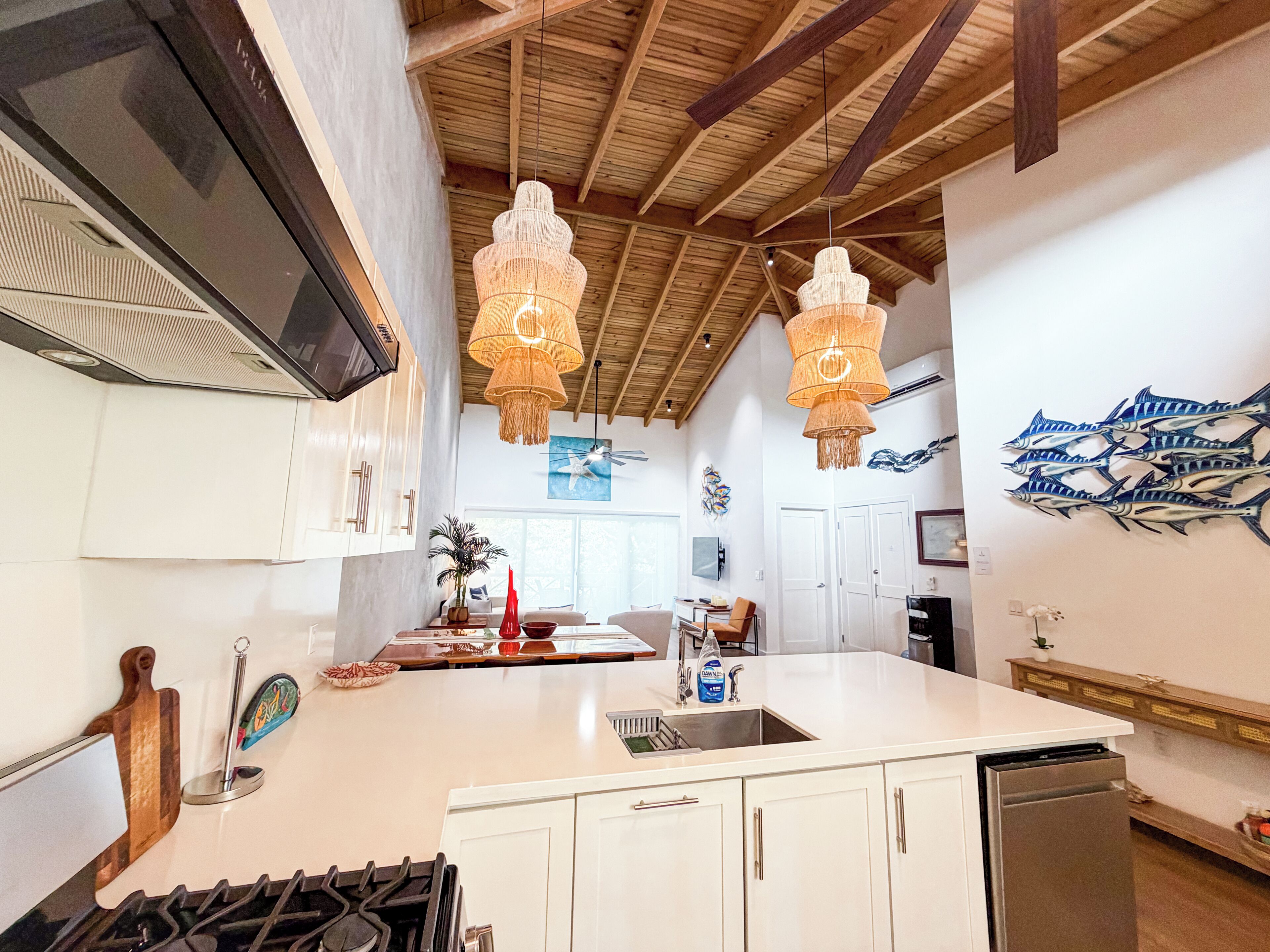A kitchen with a central island, white cabinetry, a stainless steel sink, and a gas stove.