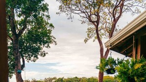 Una terraza de madera con mesas y sillas que da a un paisaje exuberante y verde.