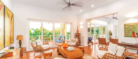 A spacious living area with wicker furniture, a wooden coffee table, and a ceiling fan.