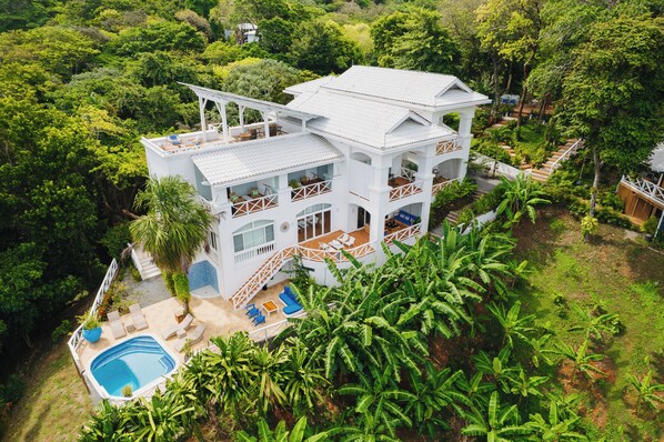 A white two-story house with a pool, surrounded by lush greenery. - Blue Roatan Resort (Roatan)