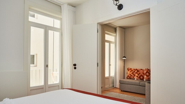 A hotel room with a large bed, a door leading to a balcony, and a sofa in the corner.