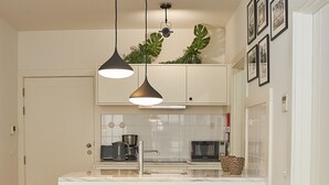 A modern kitchen with a central island, pendant lighting, and a dining area with two upholstered chairs.
