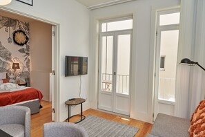 A hotel room with a bed, a TV, a balcony, and a view of the outside.