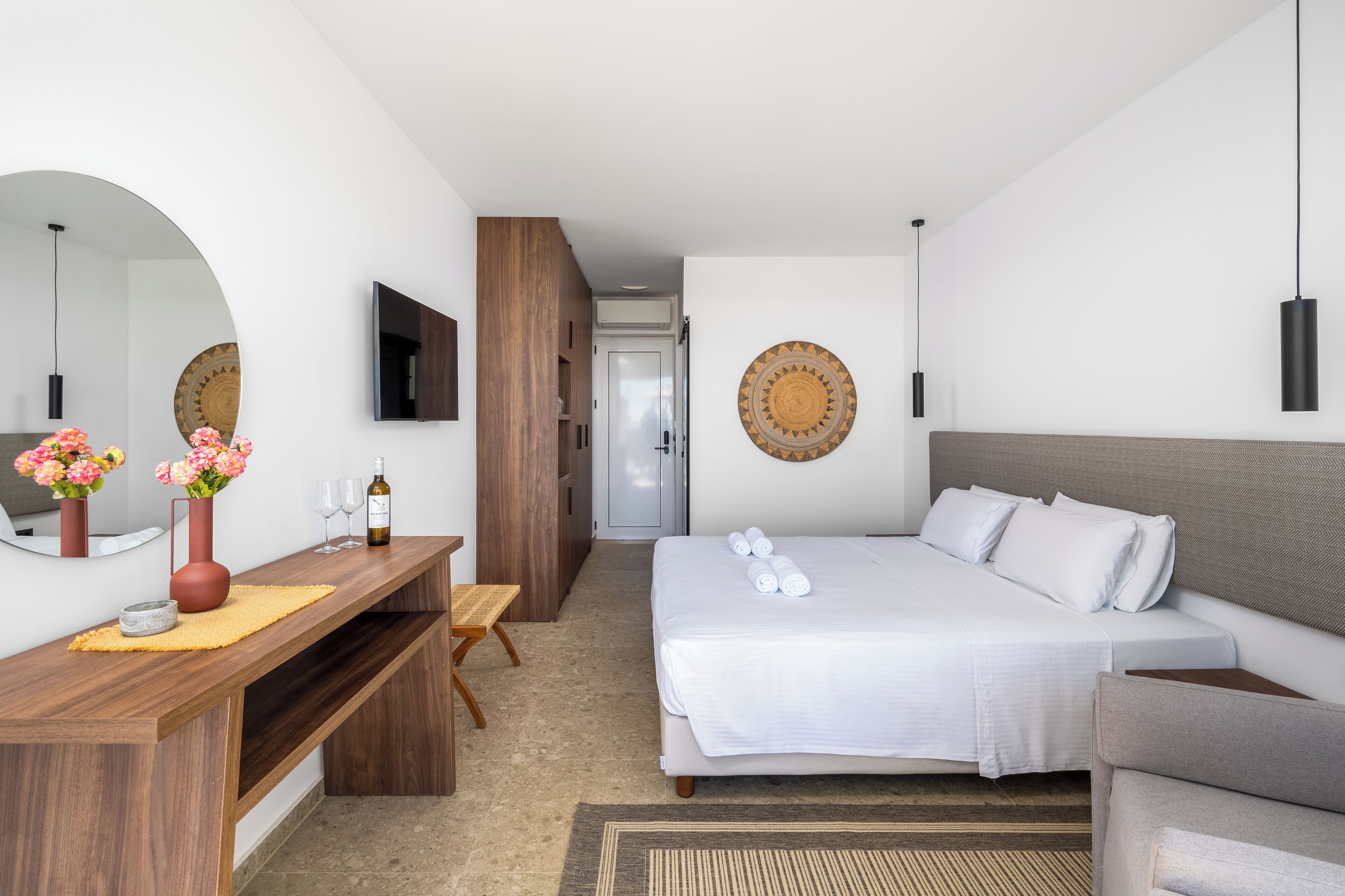 Ein modernes Hotelzimmer mit einem Bett, einem Holztisch, einem Spiegel und einem Fernseher.