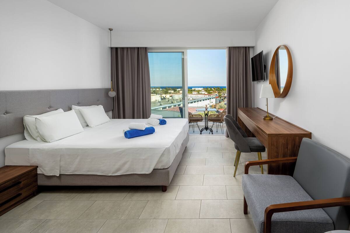 Une chambre d’hôtel moderne équipée d’un lit, d’un bureau, d’une chaise, d’une télévision et offrant une vue sur la ville.
