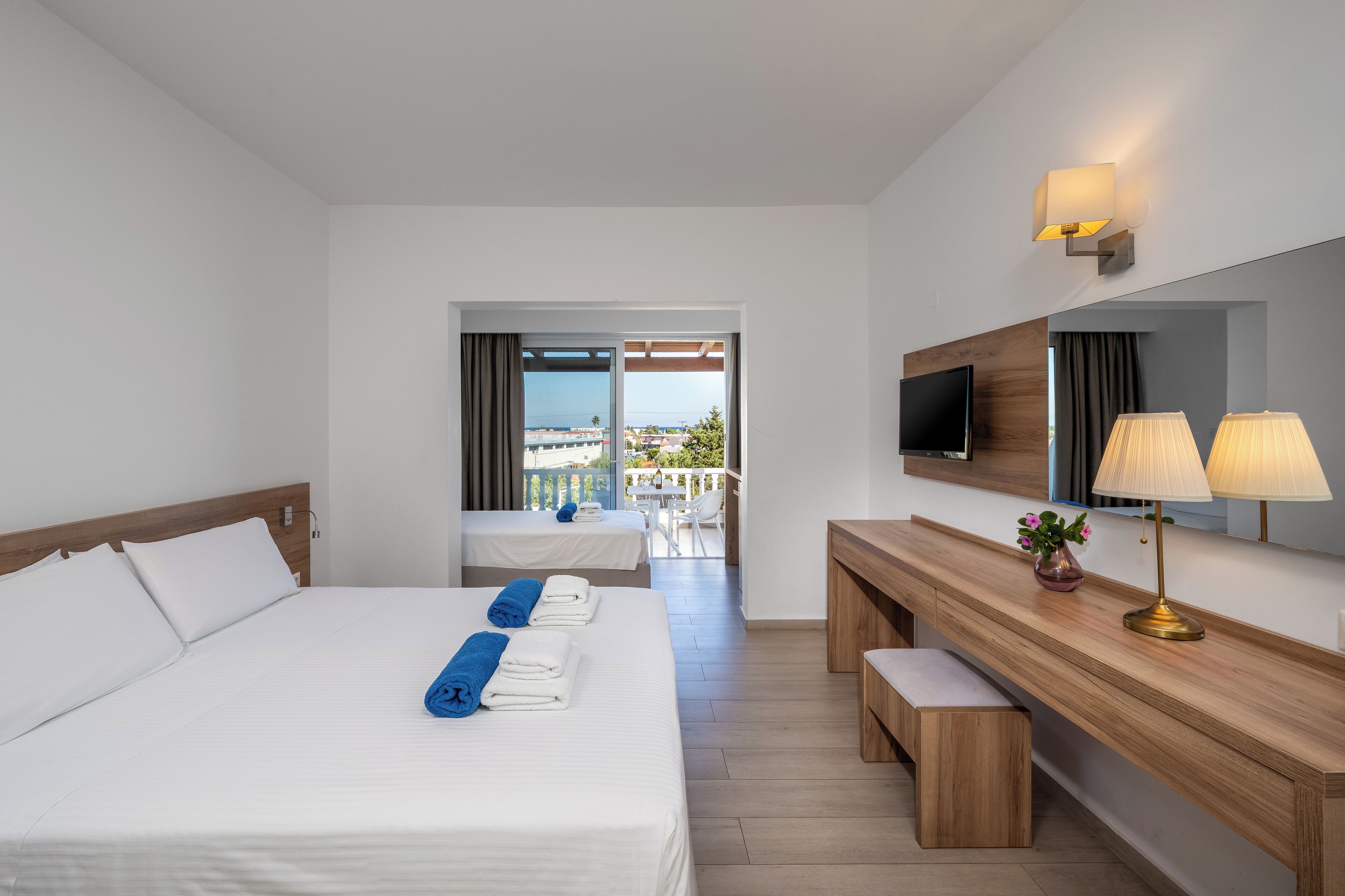 Habitación de hotel con una cama grande, un escritorio, televisión y un balcón con vistas.