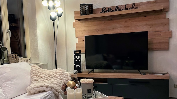 A modern living room with a wooden TV stand, a sofa, a coffee table, and a floor lamp. - Apartment zur Wiege Anhalts (Ballenstedt)