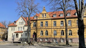 A historic building with a red-tiled roof, multiple windows, and a cobblestone street in front. - Apartment zur Wiege Anhalts (Ballenstedt)
