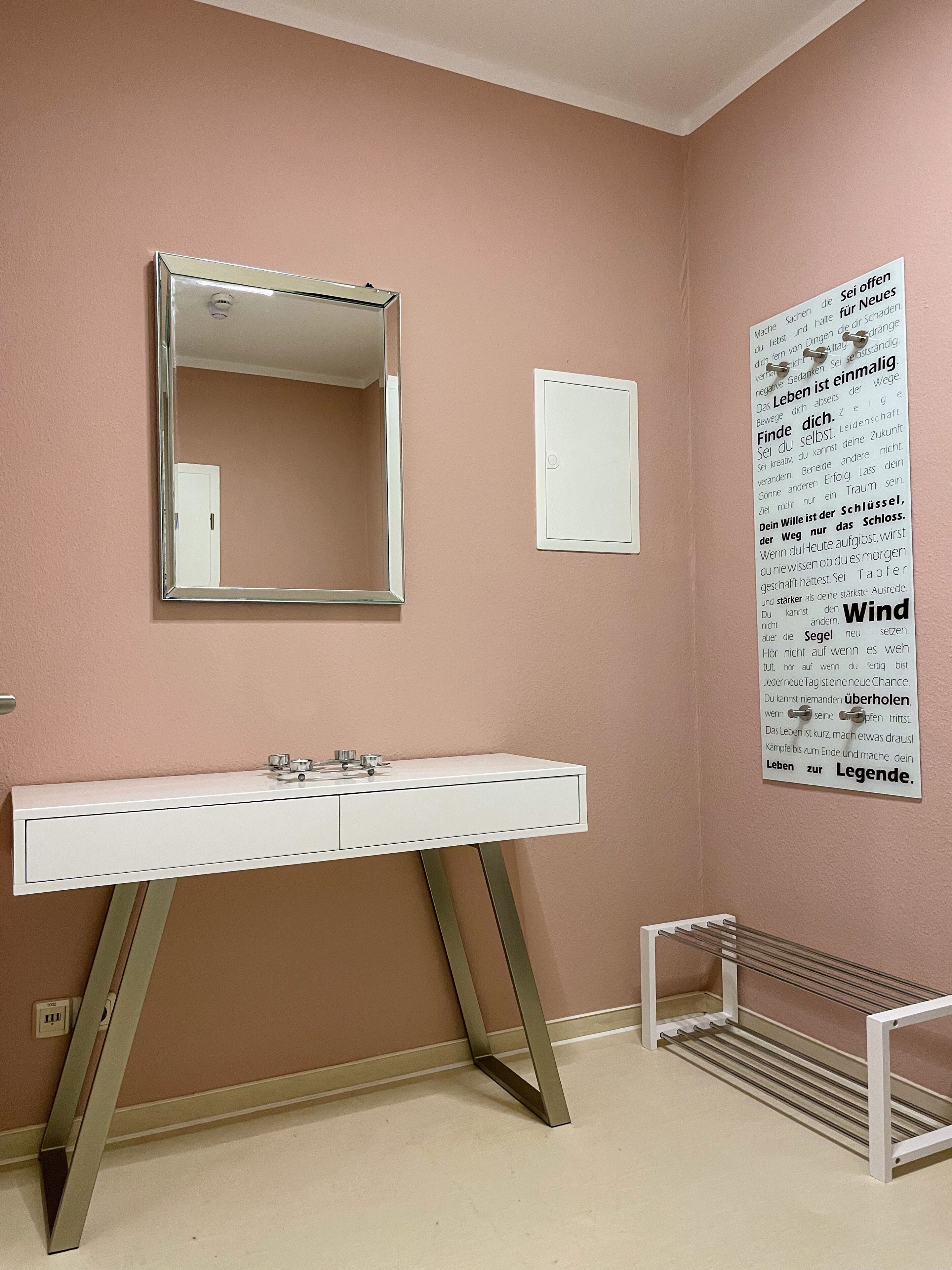A bathroom with a white vanity, a mirror, and a poster on the wall.