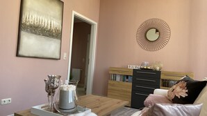 A modern living room with a wooden coffee table, a sofa with decorative pillows, a bookshelf, and a wall-mounted mirror. - Apartment zur Wiege Anhalts (Ballenstedt)