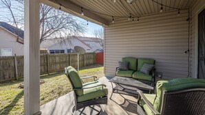 A covered patio with a green sofa, a chair, and a table. - Lexington Cutie! Entire house close to UK, hospitals,  and Keeneland (Lexington)