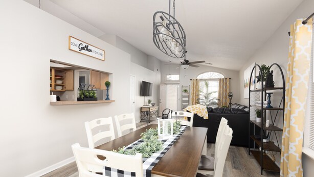A dining area with a long wooden table, white chairs, and a black and white checkered runner. There is a ceiling fan, a chandelier, and a sign that reads "Come Gather at Our Table". - Lexington Cutie! Entire house close to UK, hospitals,  and Keeneland (Lexington)