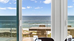 A balcony with a view of the ocean, wicker chairs, and a wooden table. - Oytstercatcher: Beachfront, Private Pool, Hot Tub, Sleeps 22! (St. George Island)