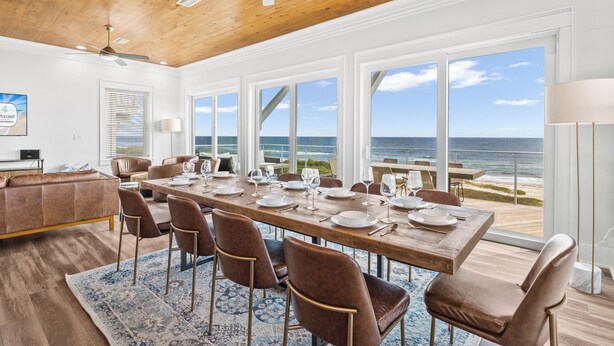 A dining area with a large table set for six, overlooking a beach. - Oytstercatcher: Beachfront, Private Pool, Hot Tub, Sleeps 22! (St. George Island)
