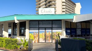 A beachfront bar and grill named 'Oceans bar & grill' with a view of the ocean through large windows.