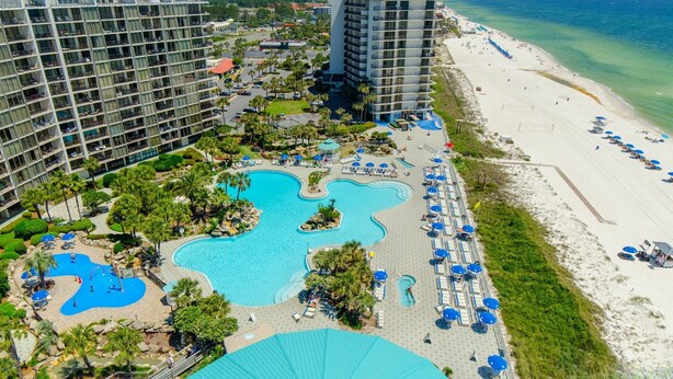 A resort with multiple swimming pools, a beach, and high-rise buildings.