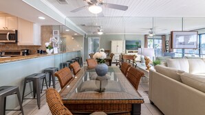 A modern kitchen with white cabinets, a microwave, and a dining area with a glass table and wicker chairs.