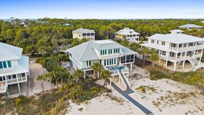 A coastal property with multiple beachfront houses, each featuring a deck and a staircase leading to the beach. - Sounds of Summer: Beachfront, Sun Deck, Screened Porch (St. George Island)