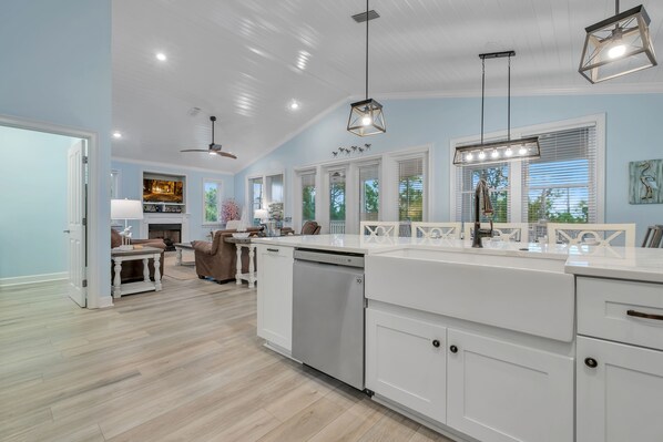 A spacious kitchen with white cabinetry, a large island, and pendant lighting.