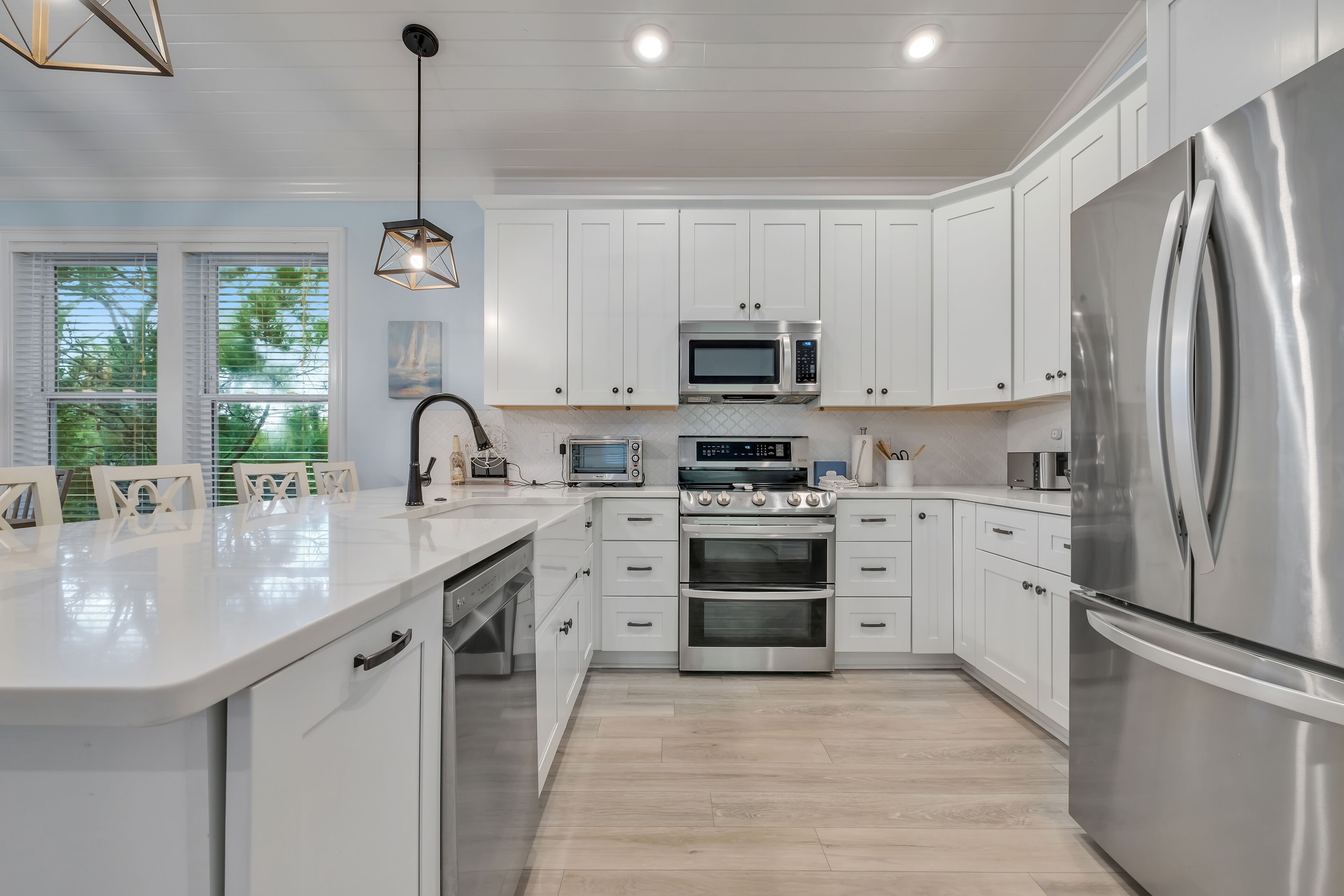 A modern kitchen with white cabinets, stainless steel appliances, and a large island.